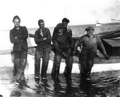 Crew members sitting on edge of motor launch, Baillie Island